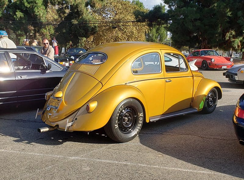 Classic yellow Volkswagen Beetle parked outdoors with black wheels.