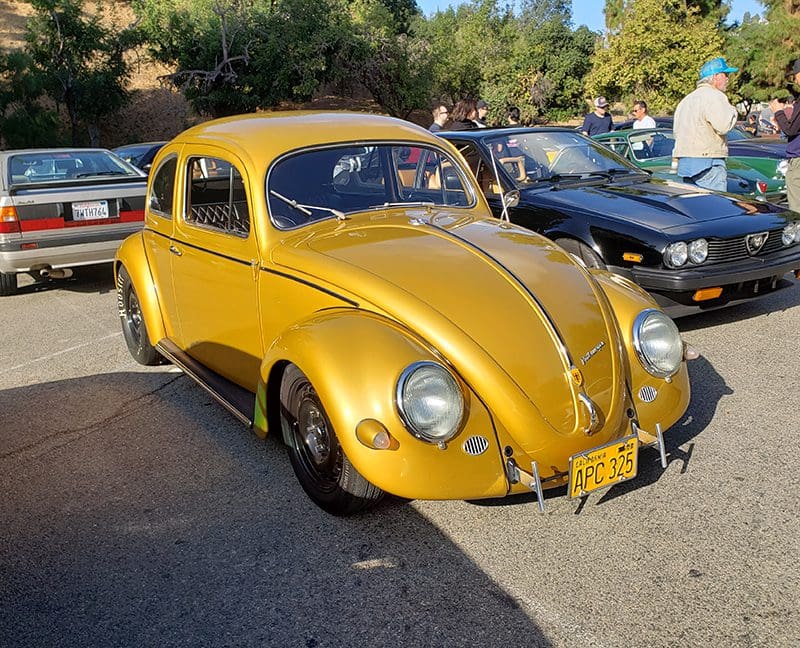 A classic yellow Volkswagen Beetle parked outdoors on a sunny day.