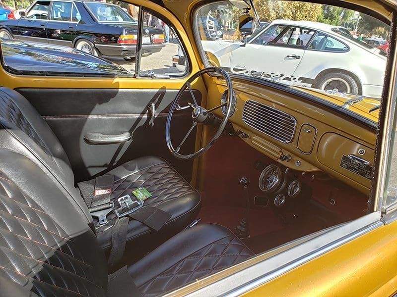 Interior of a vintage yellow car showing steering wheel and dashboard.