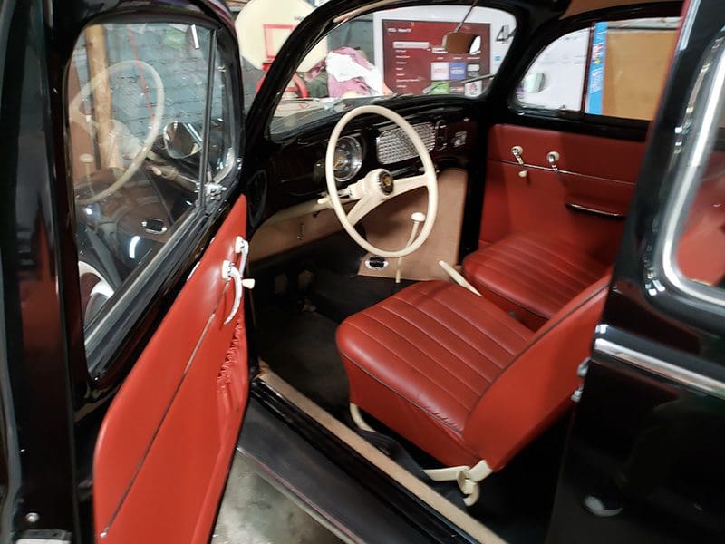 Interior of a vintage car with red leather seats and a classic steering wheel.