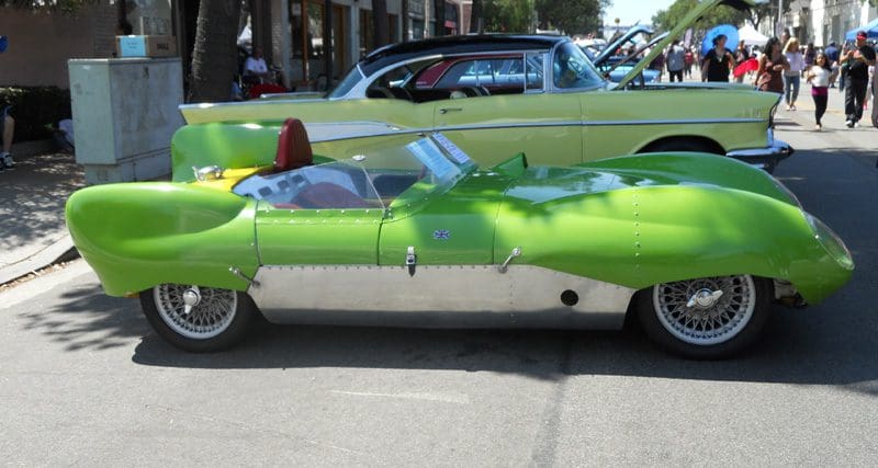 A unique lime green vintage car with a sleek design is parked outside.