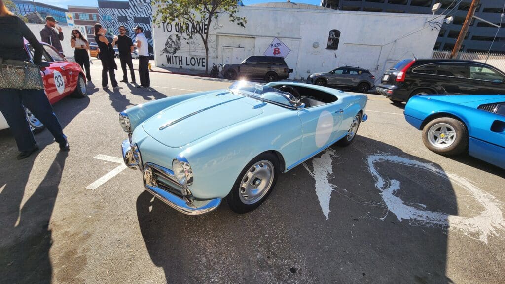 Light blue vintage convertible car parked outdoors on a sunny day.