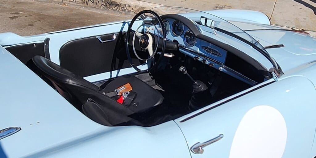 Light blue vintage convertible car parked outdoors on a sunny day.