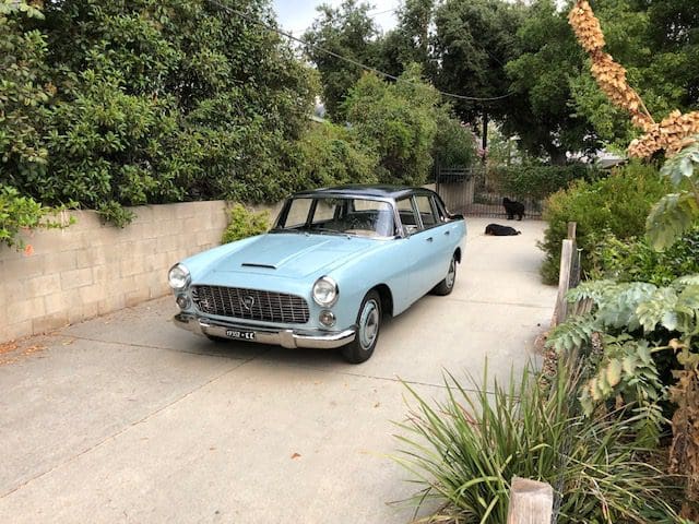 Light blue vintage convertible car parked on a driveway.