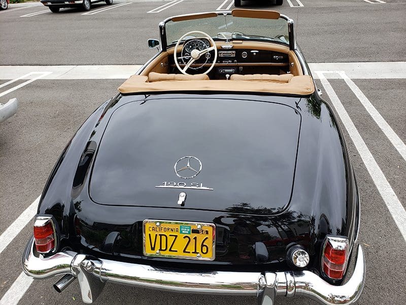 Rear view of a classic black Mercedes-Benz convertible with a yellow license plate.