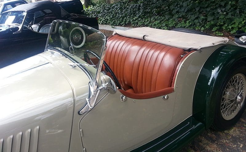 Close-up of a vintage car's brown leather interior and windshield.