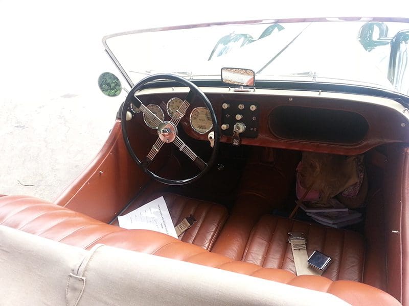 Vintage car interior with leather seats and classic steering wheel.