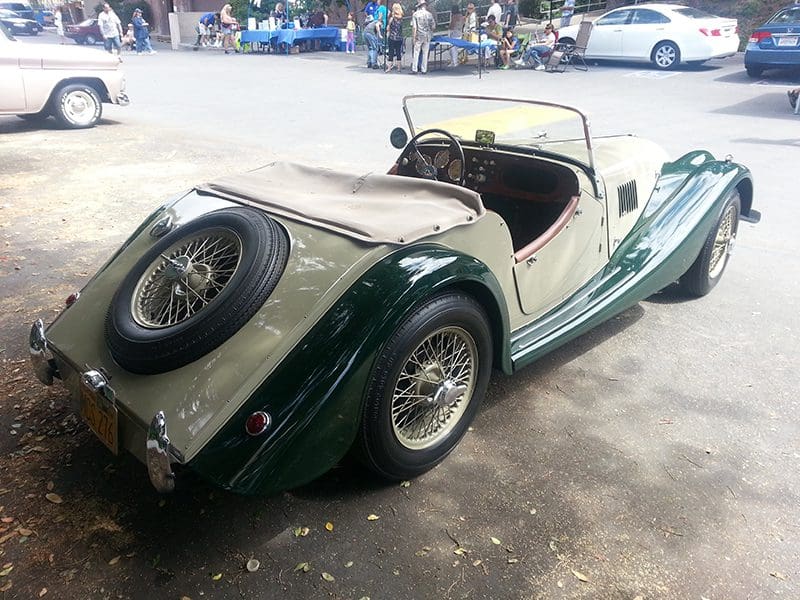Classic green convertible car with beige interior parked outdoors.