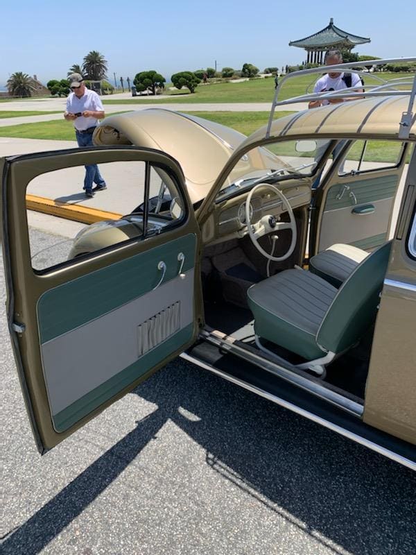 Vintage car with open door showing interior and a person nearby.