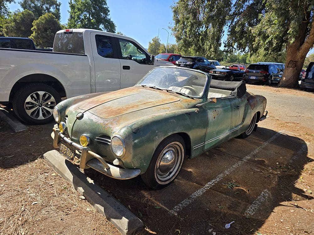 Rusty vintage convertible car parked outdoors on a sunny day.