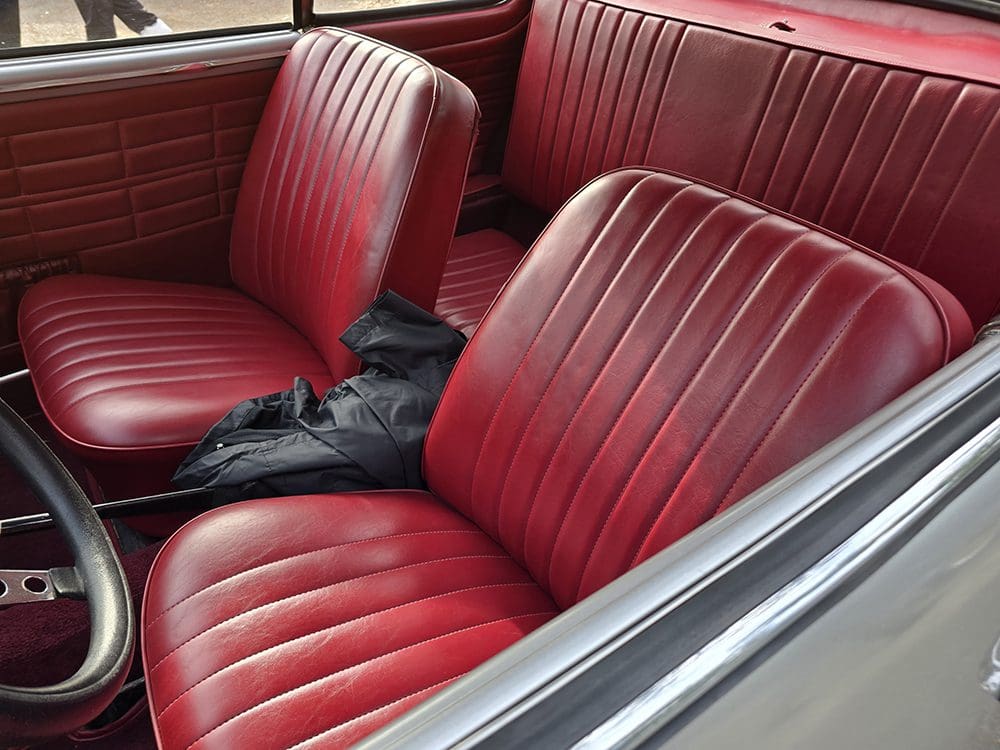 Red leather car seats with a black umbrella on the front seat.