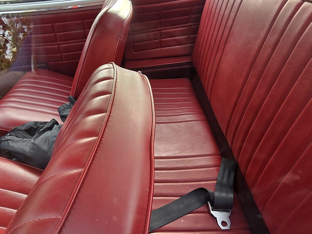 Red leather car seats with seat belts.