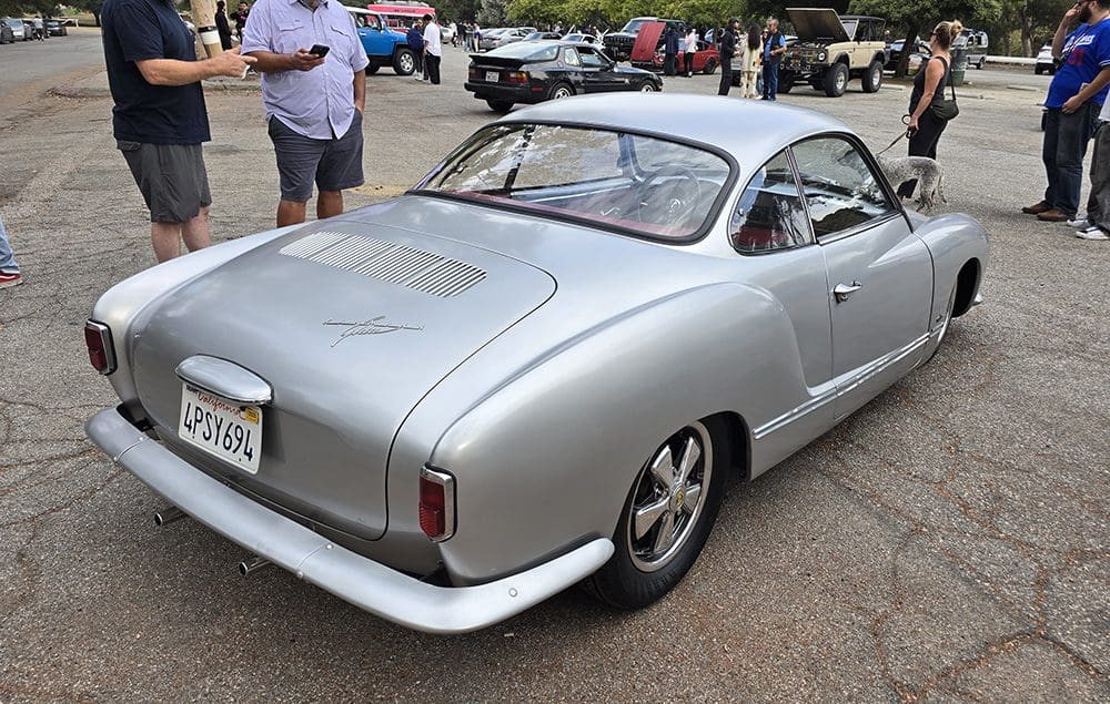 Classic silver vintage car parked at an outdoor event.