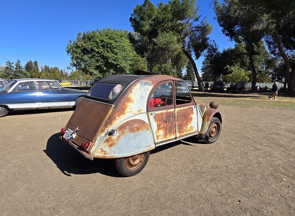 Rusty vintage car parked outdoors on a sunny day.