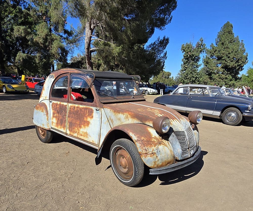 Rusty vintage car parked outdoors on a sunny day.