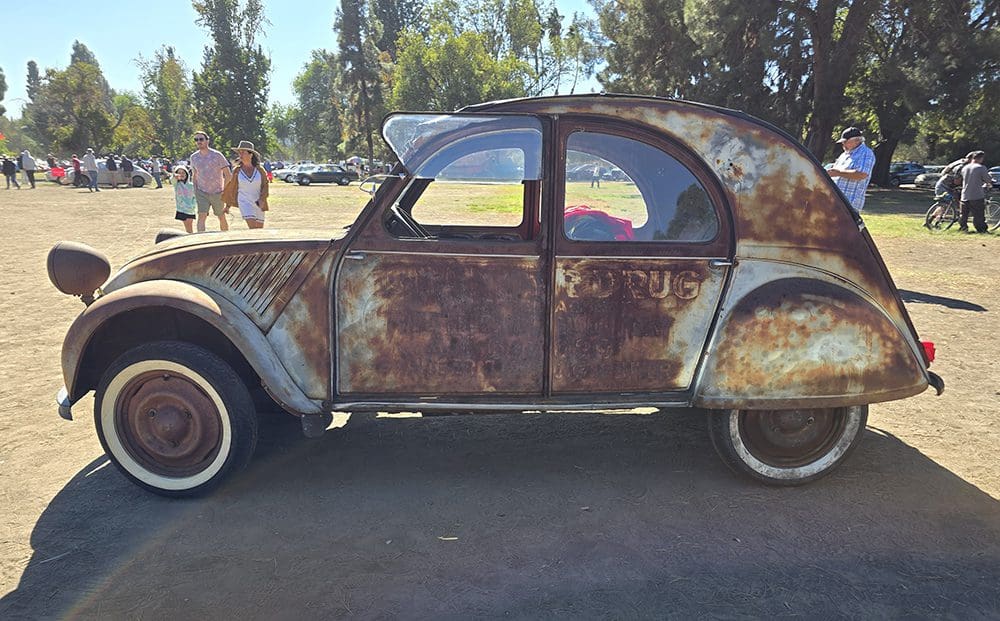 Rusty vintage car parked outdoors with visible wear and tear.