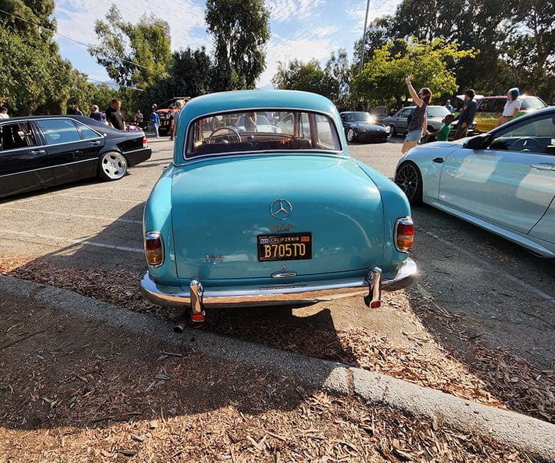 Classic blue vintage car parked outdoors among other vehicles.