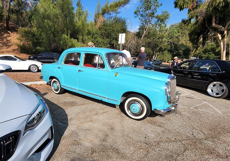 A vintage turquoise car parked outdoors on a sunny day.