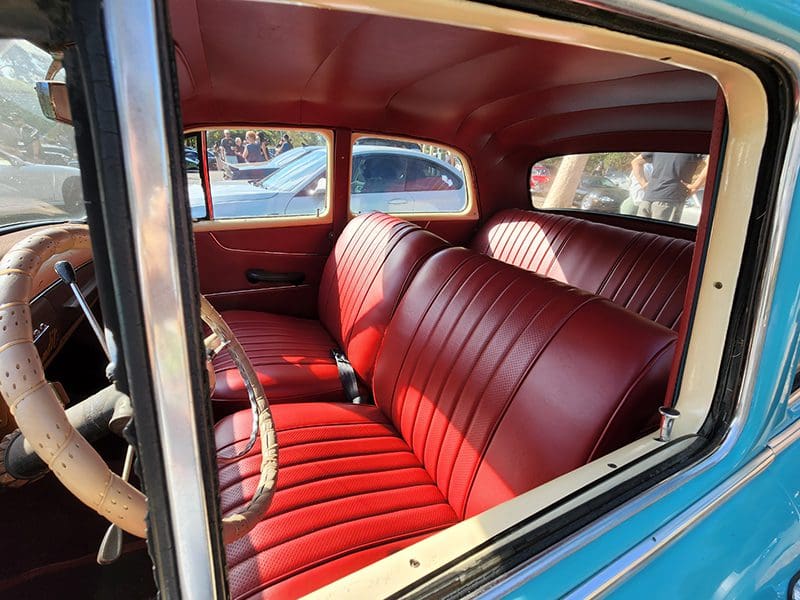 Interior of a vintage car with red leather seats and classic design.