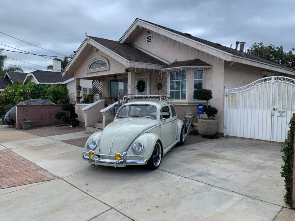 Classic Volkswagen Beetle parked in front of a suburban house.