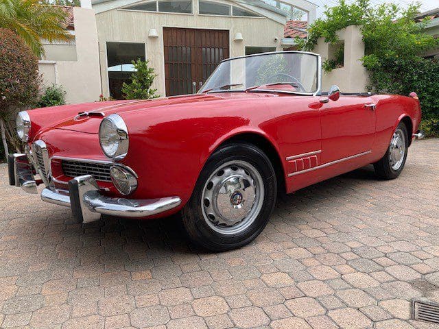 Classic red convertible car parked on a driveway.