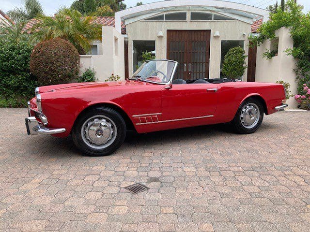 Red vintage convertible car parked on a driveway.