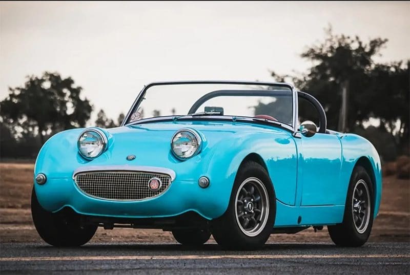 A vintage blue convertible car with a smiling front grille.