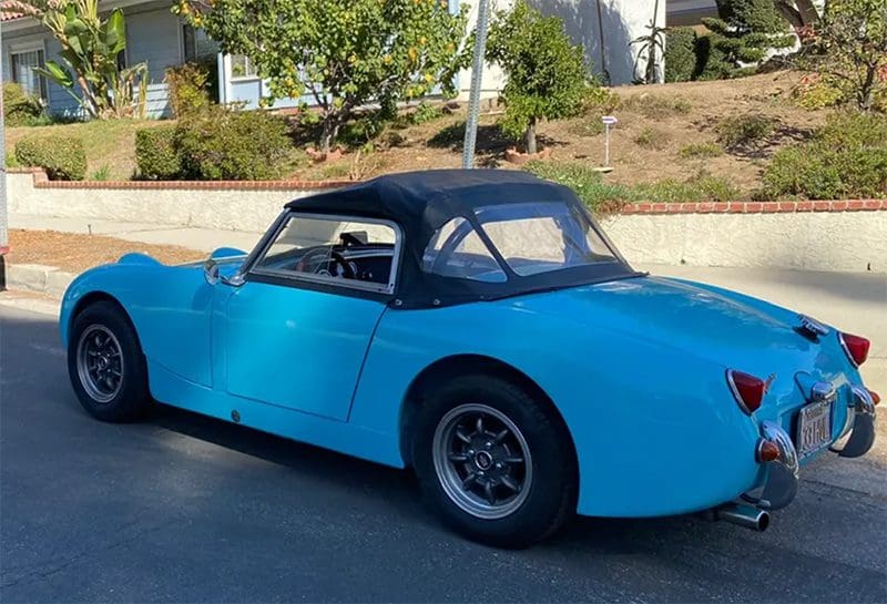 Classic blue convertible car parked outdoors on a sunny day.