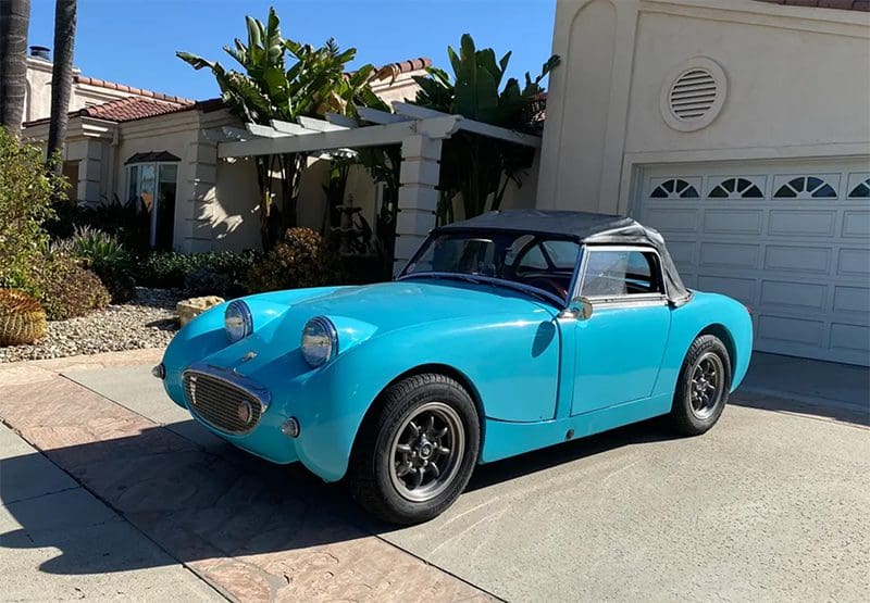 Classic blue convertible car parked in a driveway.