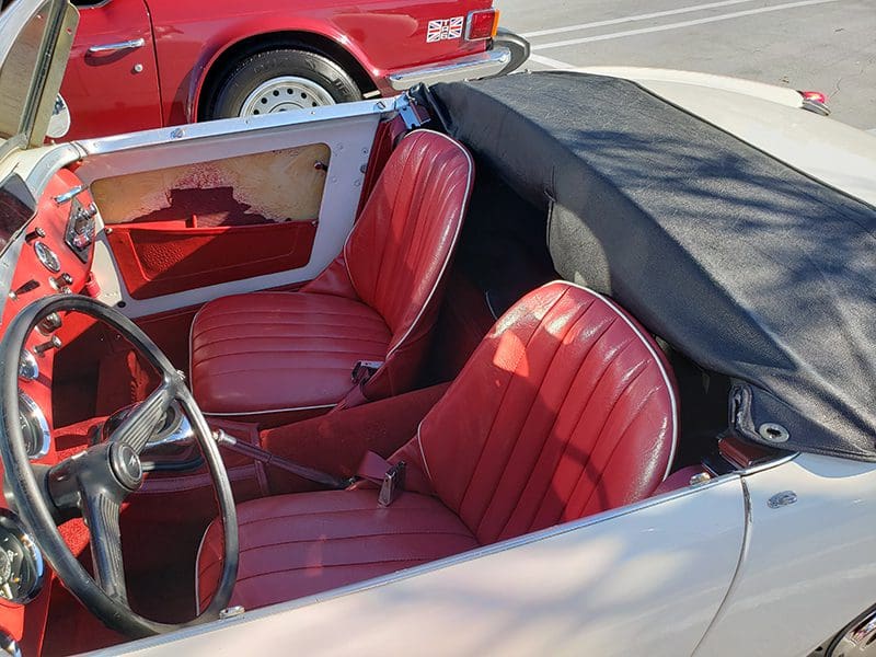 Classic convertible car with red leather seats and a black soft top.