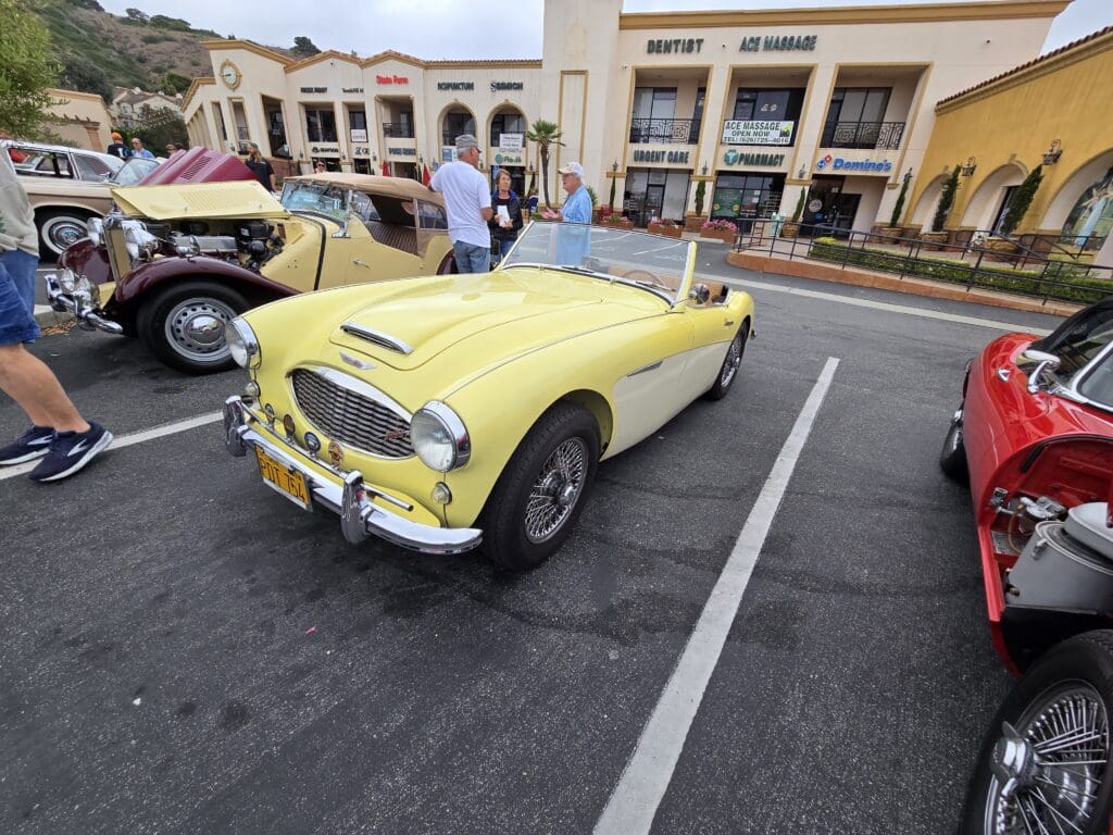 Yellow vintage convertible car parked outdoors at a car show.