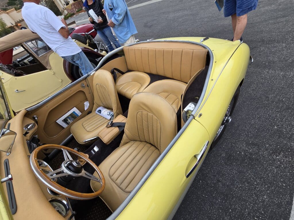 Yellow vintage convertible car parked outdoors at a car show.
