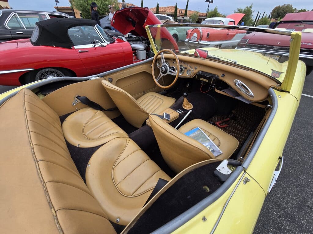 Yellow vintage convertible car parked outdoors at a car show.