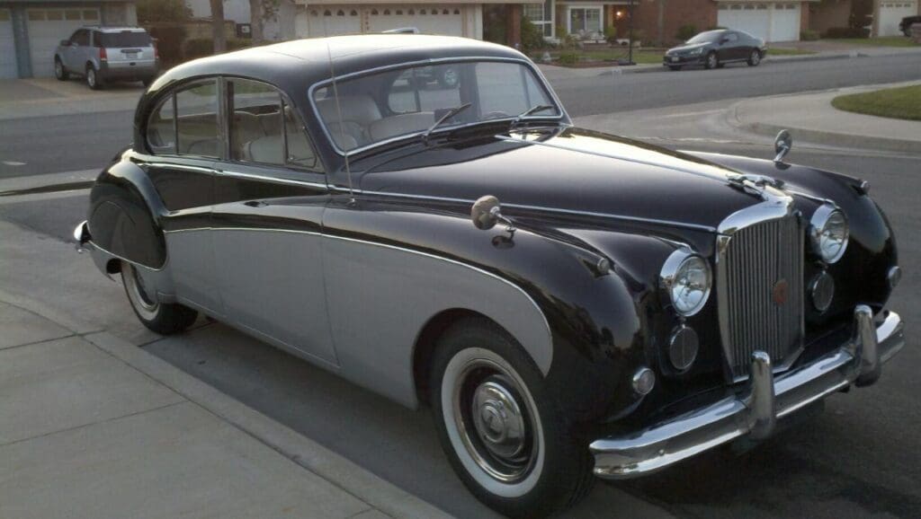 Classic black and white vintage car parked on a suburban street.