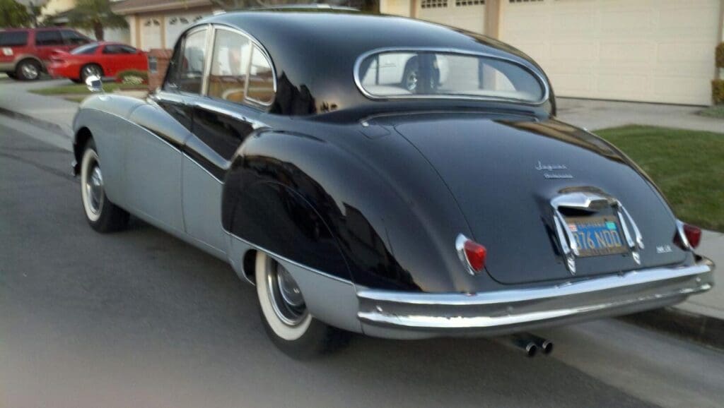A shiny black vintage car parked outside a building.