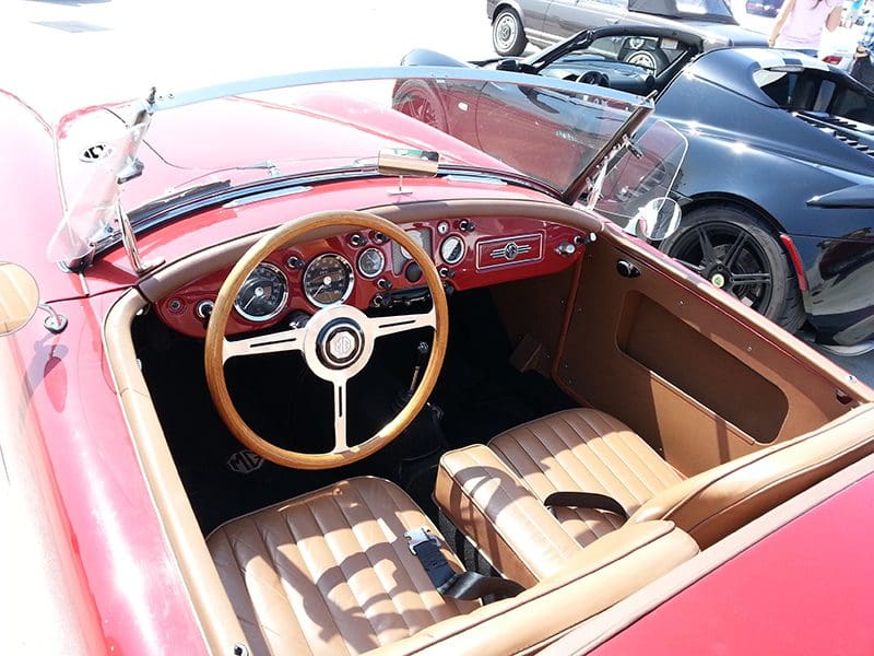 Interior of a classic red convertible sports car with tan leather seats.