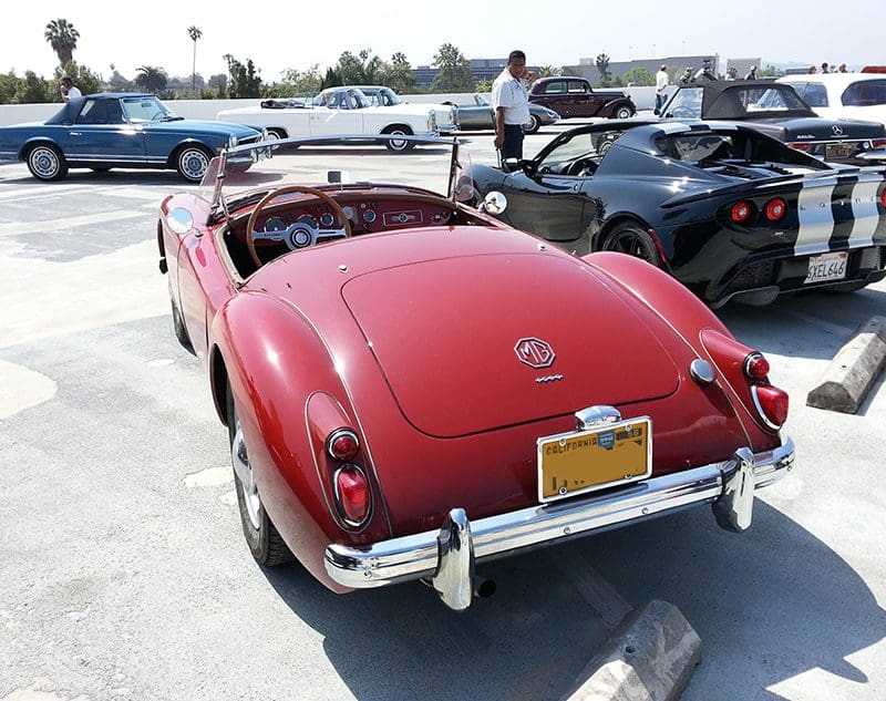 Classic red convertible car parked outdoors with other vehicles.