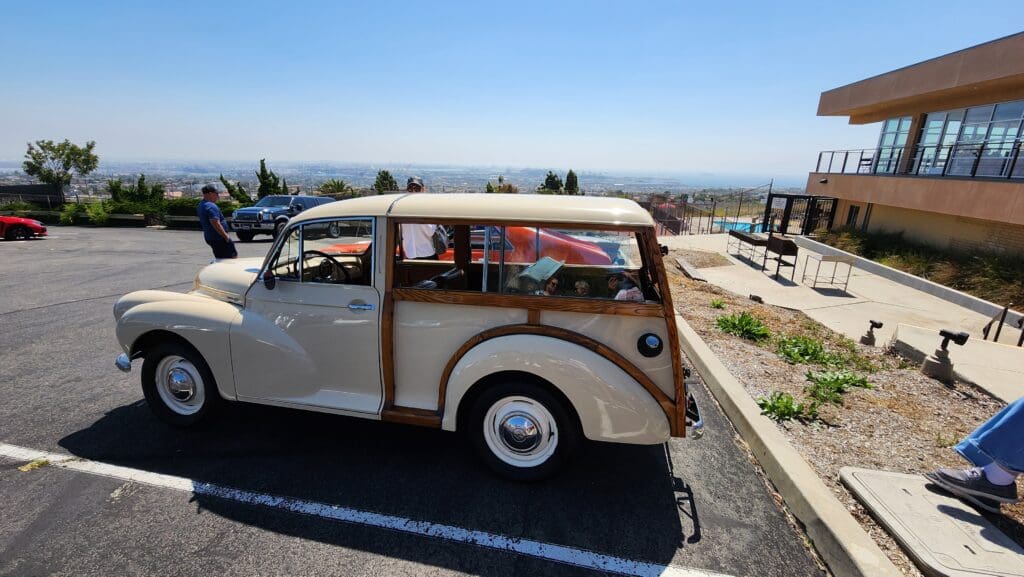 Classic cream-colored vintage station wagon parked by a scenic overlook.