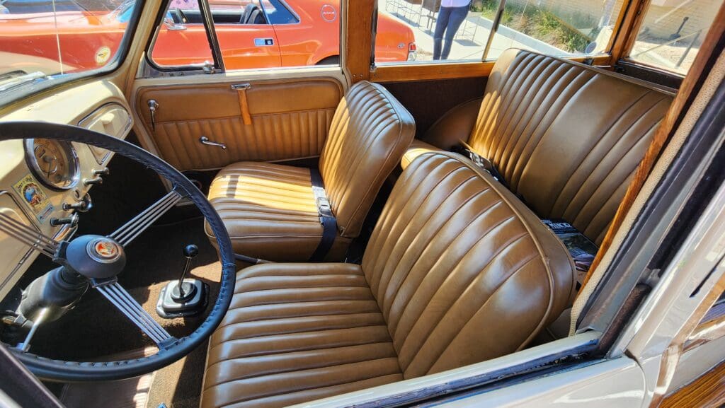 Interior of a vintage car with brown leather seats and a classic steering wheel.