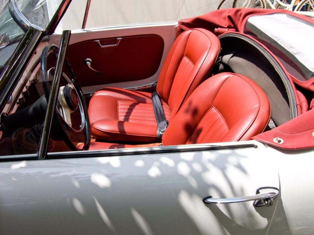 Classic red leather interior of a vintage convertible car.