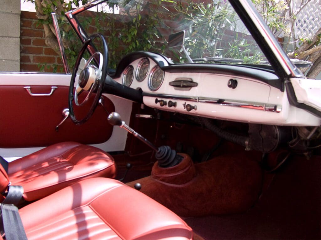 Classic car interior with red leather seats and vintage dashboard.
