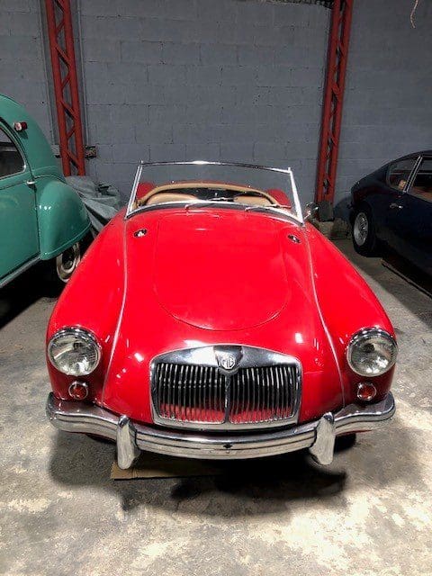 Classic red convertible MG sports car parked indoors.