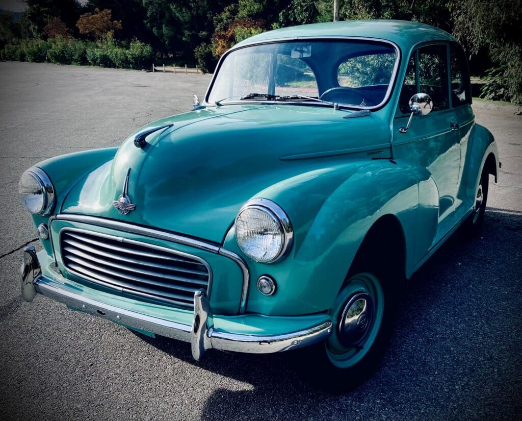 A classic turquoise vintage car parked on a sunny day.