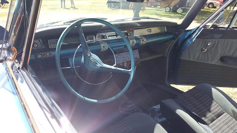 Classic car interior with vintage steering wheel and dashboard.