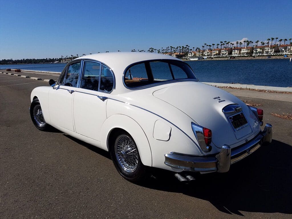 Classic white vintage car parked under clear blue sky.