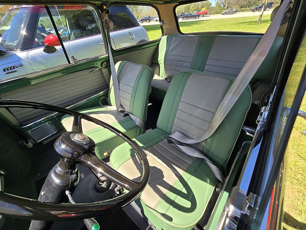 Interior of a vintage car showing green and gray seats and steering wheel.