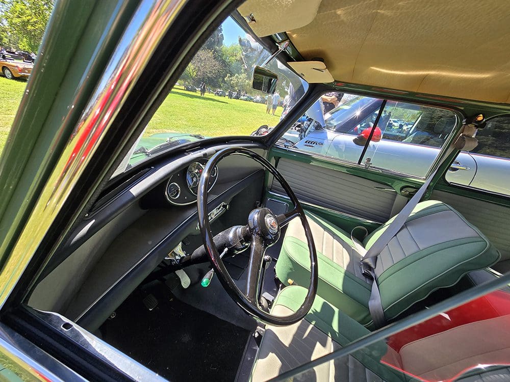 Interior view of a vintage car with green seats and a classic steering wheel.