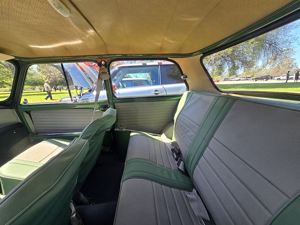 Interior view of a vintage car's backseat with green upholstery.