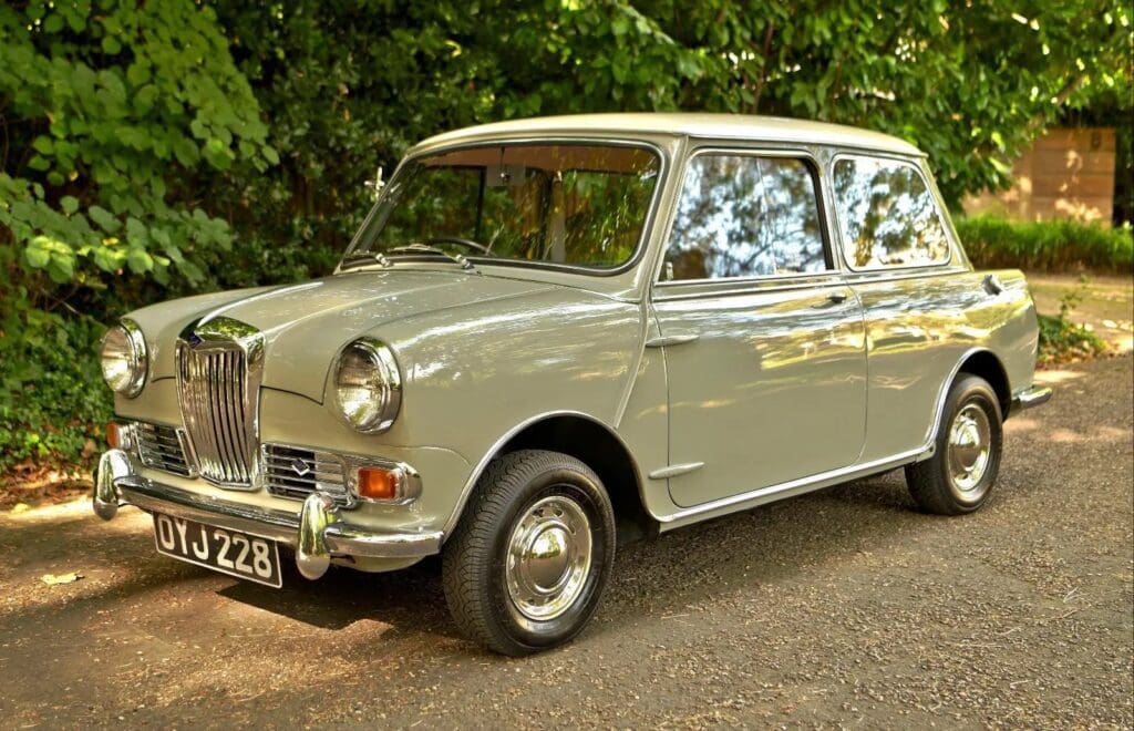 Classic silver vintage car parked on a leafy street.