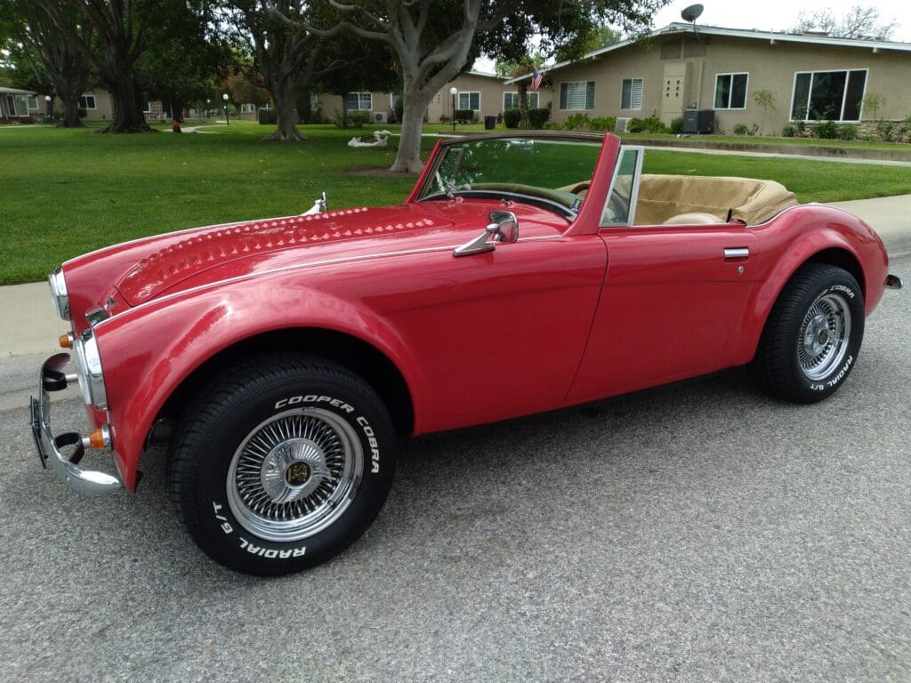 Classic red vintage convertible car parked on a driveway.